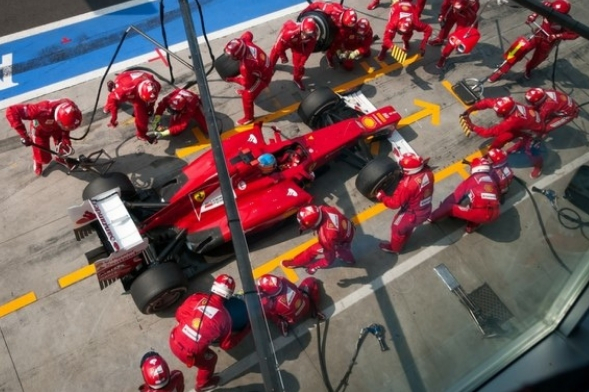 Overview of Ferrari while technicians prepare the car on boxes